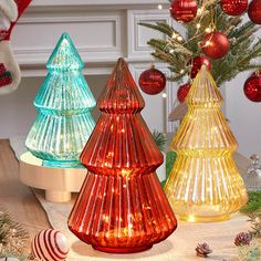 three glass christmas trees sitting on top of a table