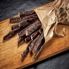 a bag full of beef sticks sitting on top of a wooden cutting board