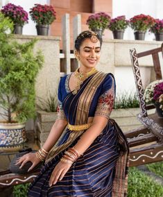 a woman sitting on top of a wooden bench wearing a blue and gold sari