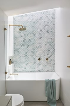 a white bath tub sitting under a window next to a toilet and shower faucet