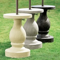 two cement pedestals sitting in the grass with an umbrella on top of one pole