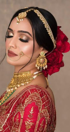 a woman in a red and gold outfit with flowers on her head, wearing jewelry