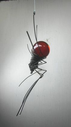 a wire sculpture with a red ball hanging from it's side and wires attached to the back