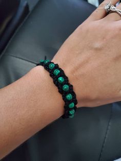 a woman's hand wearing a green beaded bracelet