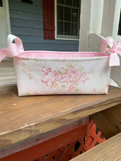 a pink and white storage bag sitting on top of a wooden bench next to a door