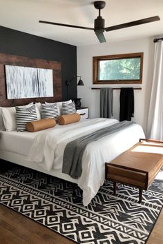 a bedroom with a large bed and wooden headboard on top of a black and white rug