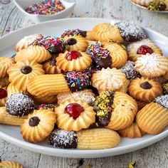 a white plate topped with cookies covered in frosting and sprinkles on top of a wooden table