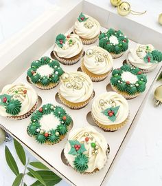 cupcakes decorated with green and white frosting in a box on a table