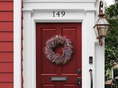 a red front door with a wreath on it and a lamp post in the foreground