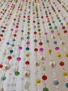 multicolored beaded necklaces are hanging on a white tablecloth with beads