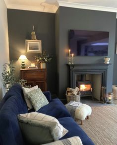 a living room filled with furniture and a fire place next to a tv mounted on the wall