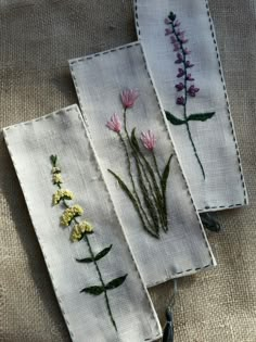 three embroidered flowers are sitting on linen