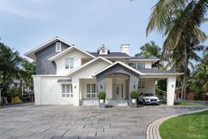 a house with a car parked in front of it and palm trees around the driveway