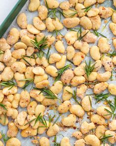 roasted potatoes with rosemary sprigs and seasoning on a baking sheet, ready to go into the oven