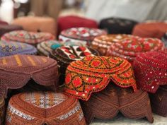 many hats are on display for sale at the market stall, including one with an ornament