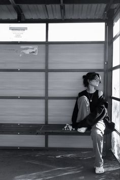 a black and white photo of a woman sitting on a bench in front of a garage door