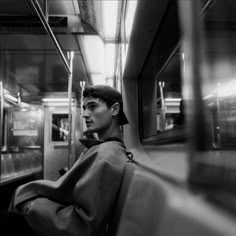 black and white photograph of a man sitting on a subway train looking out the window