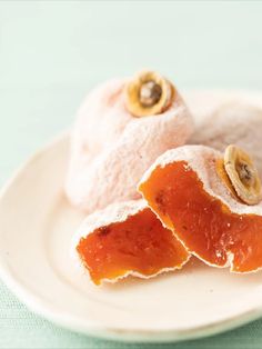 two pieces of fruit sitting on top of a white plate next to another piece of fruit