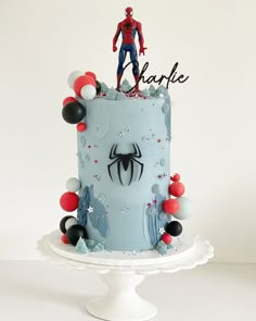 a spiderman birthday cake is decorated with balloons