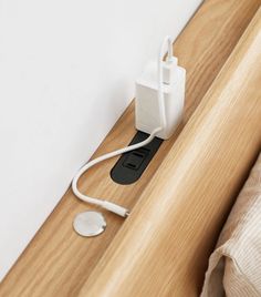 an electric outlet plugged in to a wall mounted charger on the side of a bed