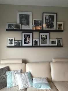 a white couch with pillows and pictures on the wall above it in a living room