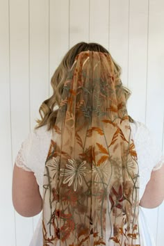 the back of a woman's head wearing a veil with flowers and leaves on it