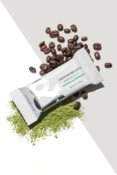 an open bar of coffee beans next to some green powder on a white and gray background