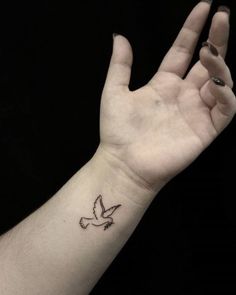 a person's hand with a small bird tattoo on their left wrist and the word peace written below it