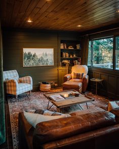 a living room filled with furniture and a painting hanging on the wall above it's windows