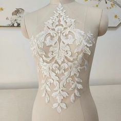 a mannequin with white lace on it's back and flowers in the background