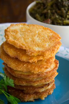 a stack of fried food sitting on top of a blue plate next to a bowl of green beans