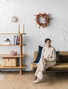 a woman sitting on top of a couch next to a book shelf