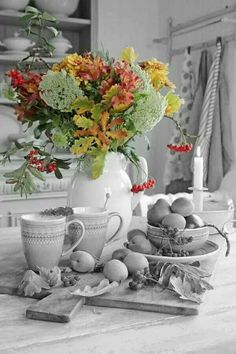 a vase filled with flowers sitting on top of a table next to fruit and vegetables