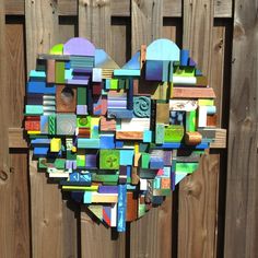 a heart shaped sculpture made out of various colored wood blocks on a wooden fence post