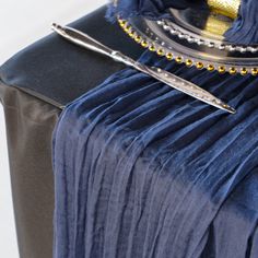 a table topped with a blue cloth and a silver plate covered in beads next to a black bag