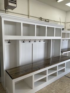 an empty room with several white shelves and wooden benches in front of the bench is also built into the wall