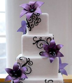 a three tiered cake with purple flowers on the front and side is displayed on a computer screen