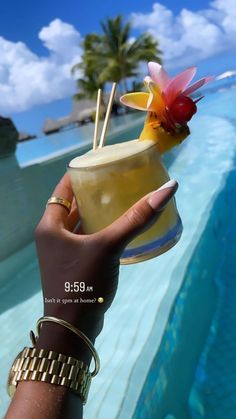 a person holding up a drink in front of the ocean with a bird on it