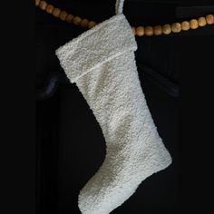 a white christmas stocking hanging from a wooden bead necklace on a black background