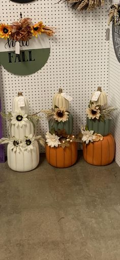 three pumpkins are sitting in front of a wall