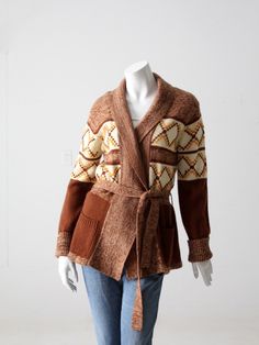 "This is a 1970s vintage cardigan sweater. Warm marbled brown tones color the acrylic sweater with a cream geometric pattern.  The hippie sweater wraps closed with a knit belt closure.  There are pockets on the waist. CONDITION In good condition with wear consistent with age and use.  MARKED SIZE: M MEASUREMENTS Bust: 36\"  ..  91.4 cm Length: 26.5\"  ..  67.3 cm Shoulders: 17\"  ..  43.2 cm Outside Sleeve:  26\"  ..  66 cm Outside Sleeve Cuffed:  23\" ...  58.4 cm HOW WE MEASURE → Sweater measu Sweater Wraps, Hippie Cardigan, Hippie Sweater, Irish Wool Sweaters, Knit Belt, Hippie Sweaters, Hipster Tops, Vintage Cardigan Sweater, Belted Sweater