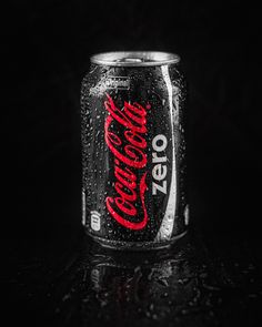 a can of coca - cola on a black surface