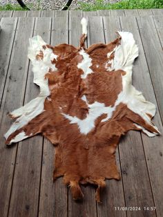 a brown and white cow skin laying on top of a wooden floor