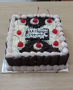 a black and white birthday cake with cherries on it