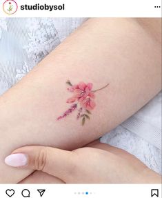 a woman's arm with pink flowers on it and her left hand holding the arm