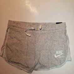 Nike Women's Sportswear Slim Fit Shorts Medium Slim Fit Shorts Elastic Waistband With Drawcord For Custom Fit Open Hand Side Pockets Nike Logo Graphic At Hemline Color: Grey Cotton Bottoms With Drawstring For Sports, Sporty White Athletic Shorts With Drawstring, Nike Cotton Joggers For Workout, White Activewear With Drawstring For Sports, Nike White Leisure Bottoms, Sporty Cotton Athletic Shorts For Workout, Cotton Workout Shorts For Sports Season, Nike Casual Joggers For Workout, Stretch Cotton Shorts For Sports Season