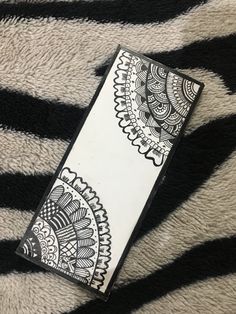 a black and white pattern on the back of a cell phone case sitting on top of a zebra print blanket