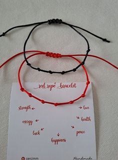 three bracelets with words on them sitting on top of a white sheet that says red rope bracelet