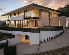 a modern house with large windows and balconies on the top floor at dusk