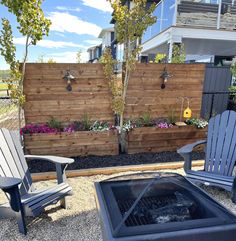 two adiron chairs sitting next to each other in front of a wooden fence and fire pit